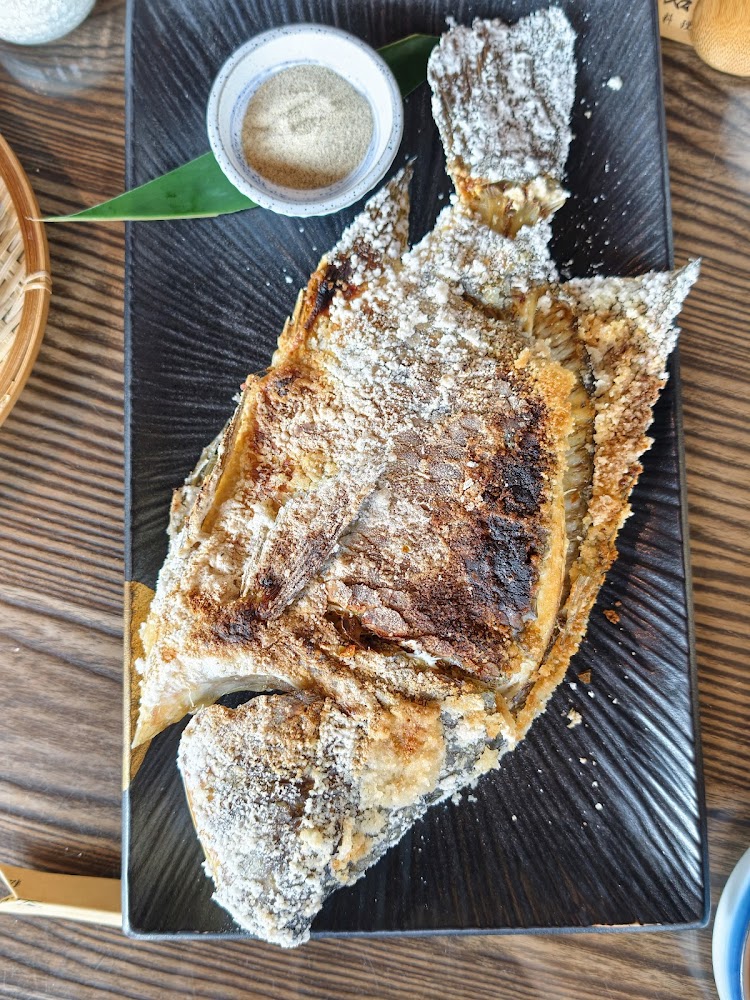 表面撒著鹽粒的金黃酥脆烤魚搭配沾料小碟