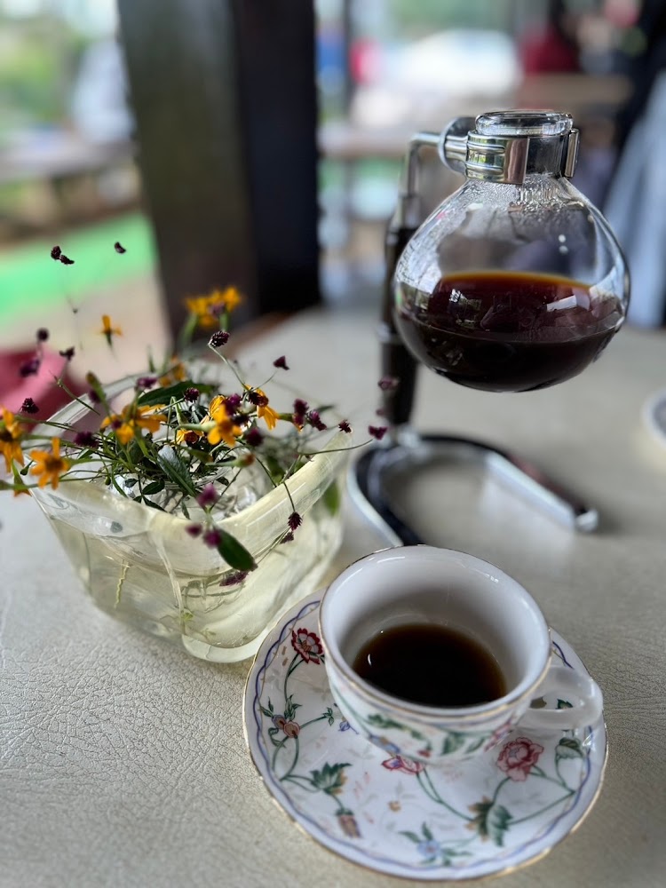 精美花紋杯碟上的黑咖啡與虹吸壺