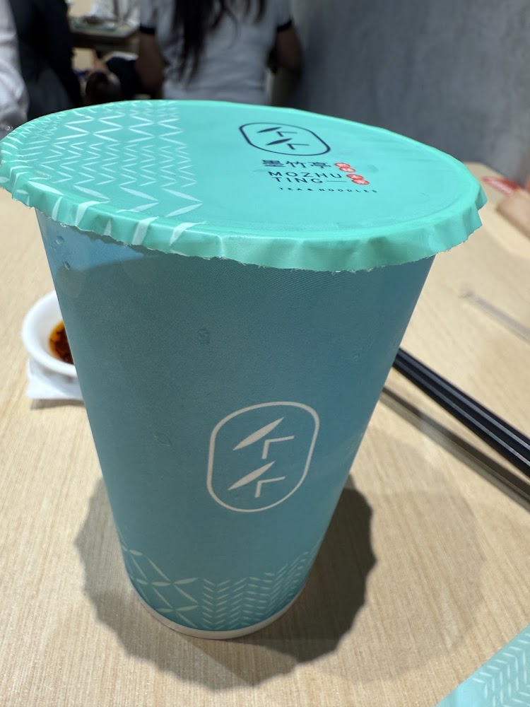 墨竹亭品牌外帶飲料杯，藍綠色杯身印有品牌標誌。