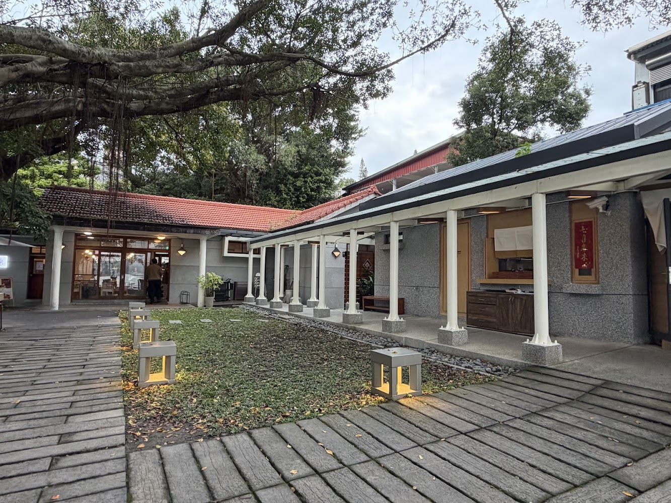 紅瓦屋頂與白色柱廊的建築,前方有庭院石板步道