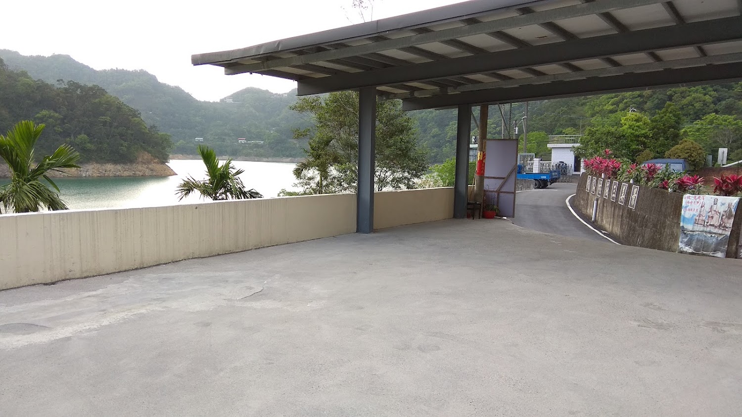 湖邊水泥平台與綠色山丘景觀