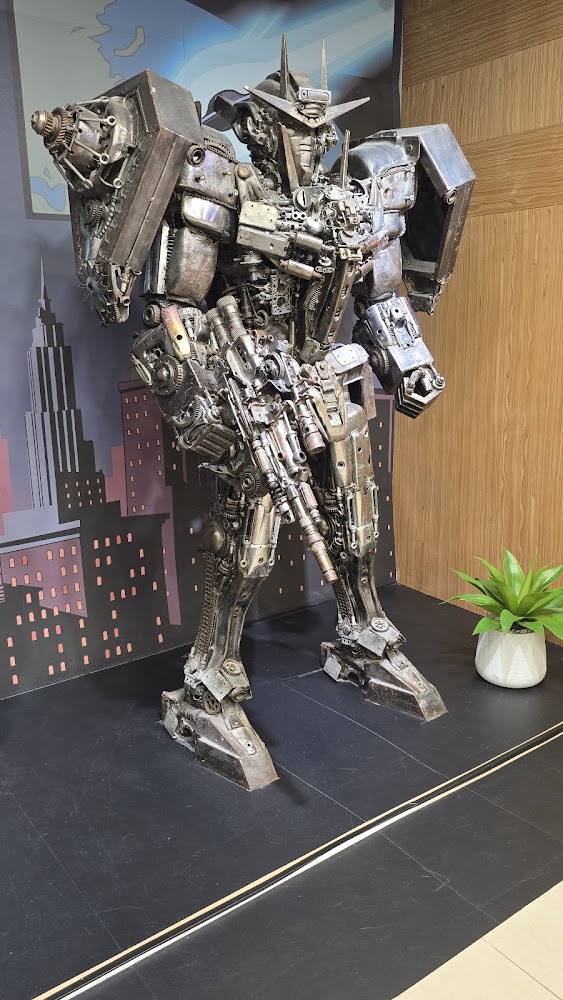 金屬零件組成的大型機器人雕像，背景有城市高樓圖樣