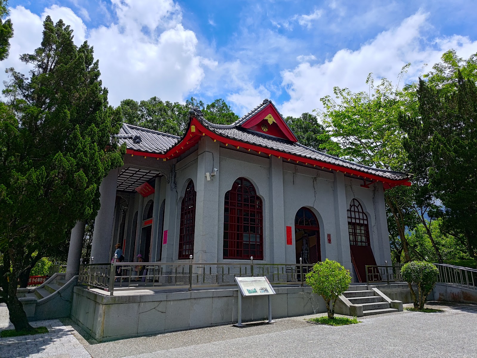 玄光寺正面外觀，灰白色廟身配紅色門窗，日式廟宇風格，藍天白雲綠樹環繞