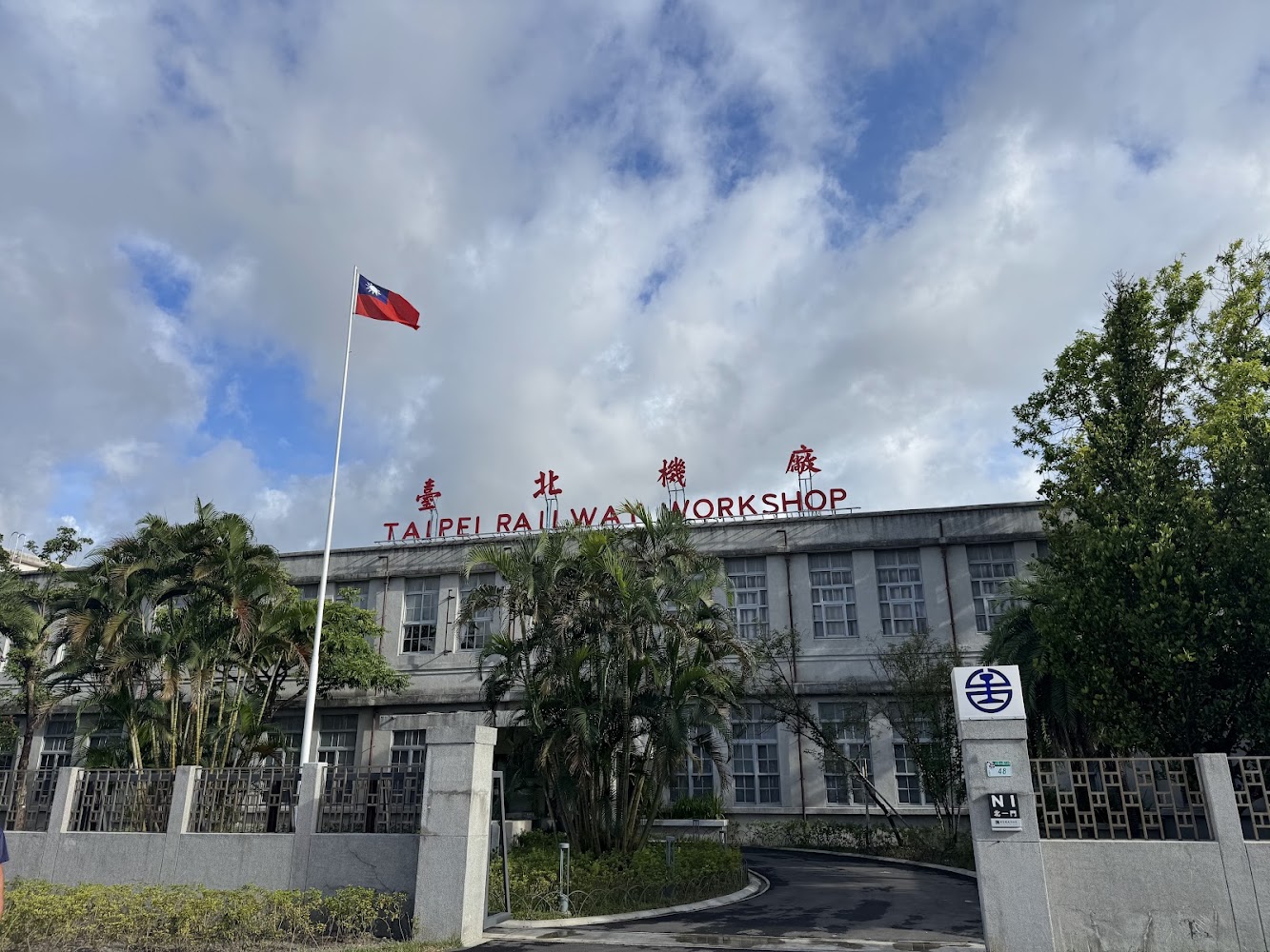 台北機廠歷史建築外觀，上方有TAIPEI RAILWAY WORKSHOP字樣與國旗。