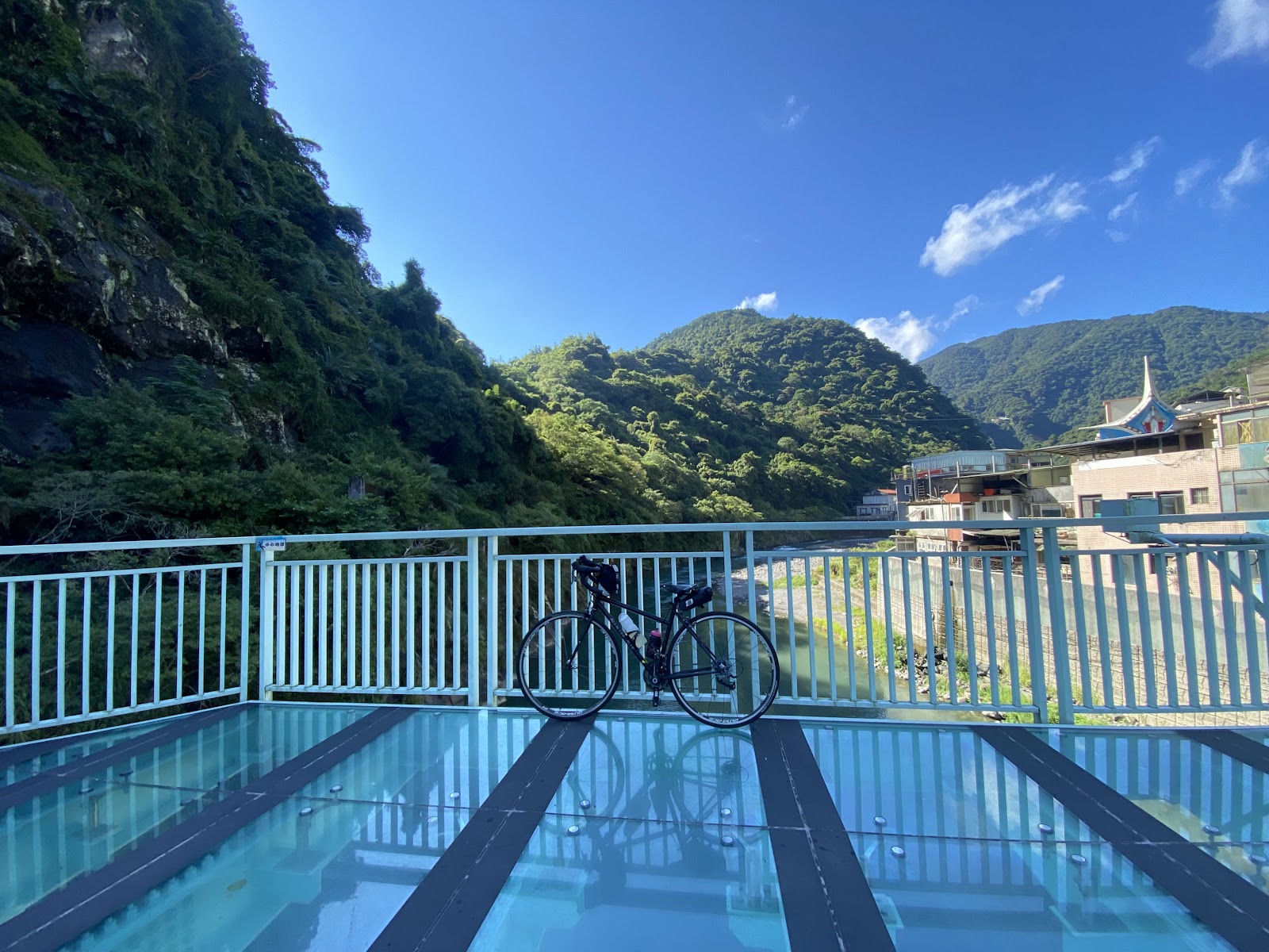 烏來玻璃吊橋，欄杆旁停放腳踏車，背景翠綠山谷與藍天