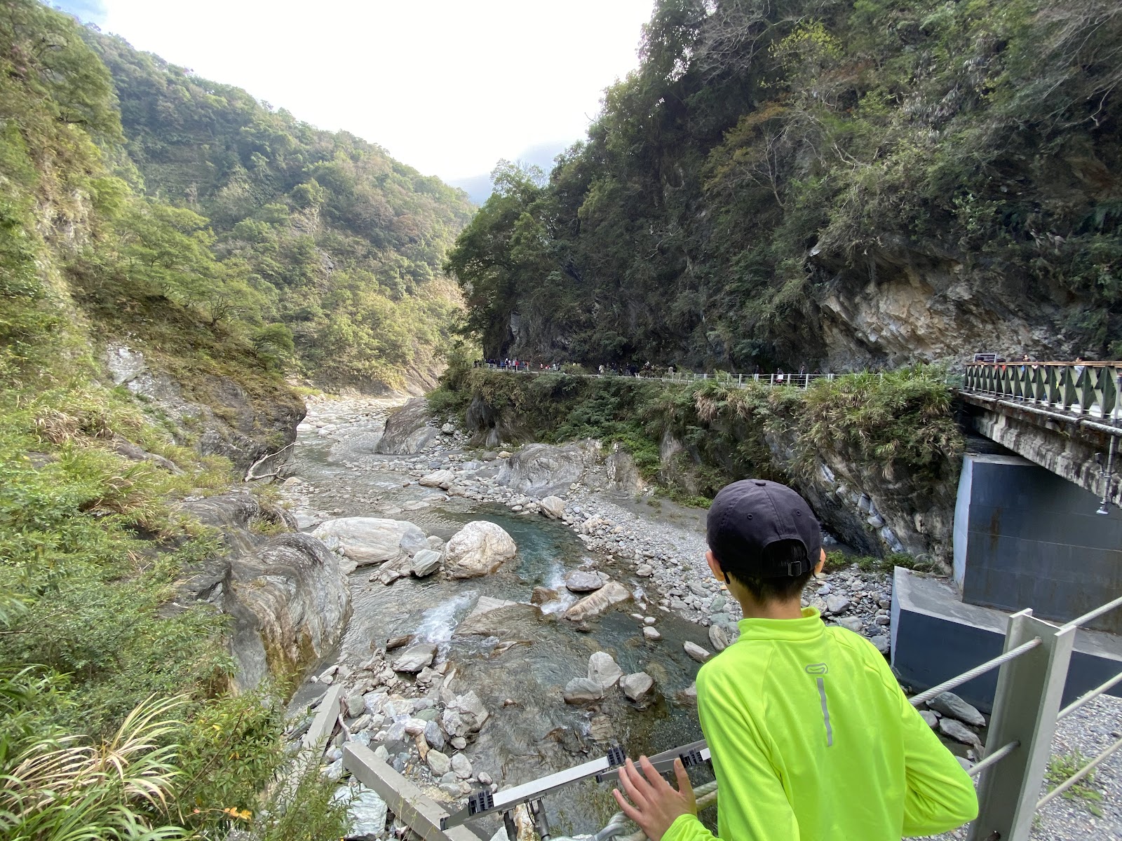 白楊步道溪谷，遊客俯瞰清澈溪流與礫石河床，兩側青山相夾，自然景色清新迷人