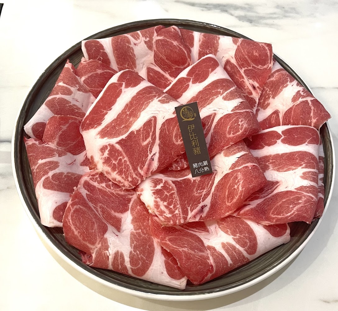 一盤新鮮伊比利豬肉火鍋片，色澤紅潤油花均勻。
