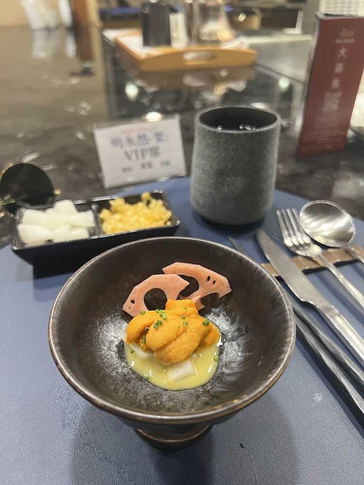 精緻高檔餐點上有海膽與蓮藕片，旁邊搭配茶杯與餐具