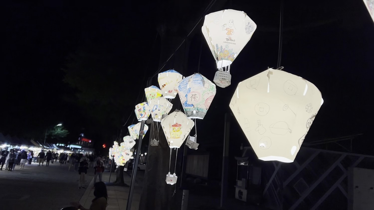 夜晚點亮的熱氣球燈籠與熱鬧市集人潮