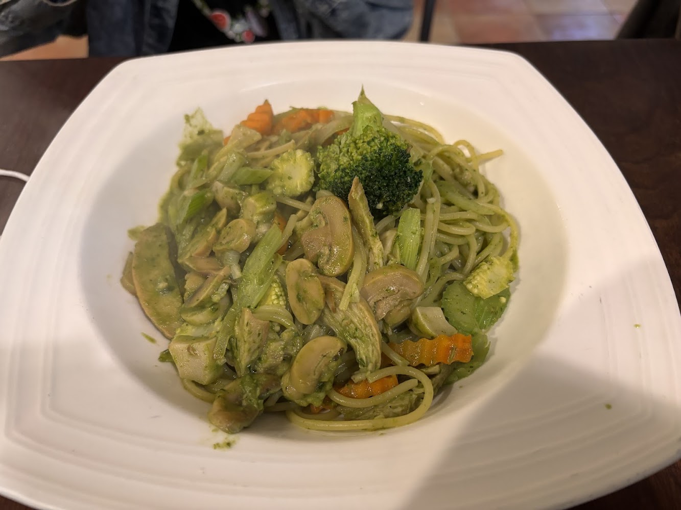這是一盤蔬菜義大利麵，裡面有西蘭花、蘑菇、芹菜、紅蘿蔔等各種蔬菜，拌著青醬，看起來健康又美味。