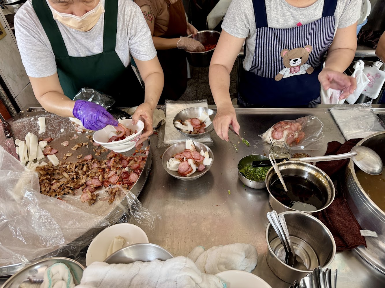 兩位工作人員在準備白色粿類、肉品與醬料