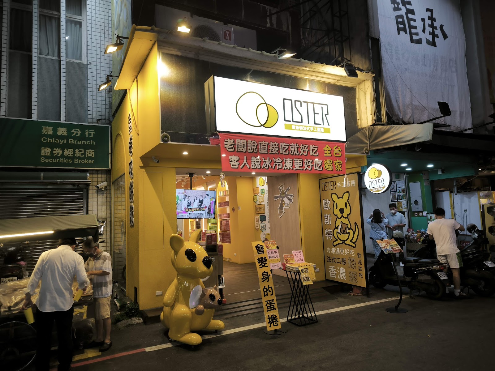 文化路觀光夜市入口，黃色吉祥物公仔，攤販燈火通明，人潮熙攘