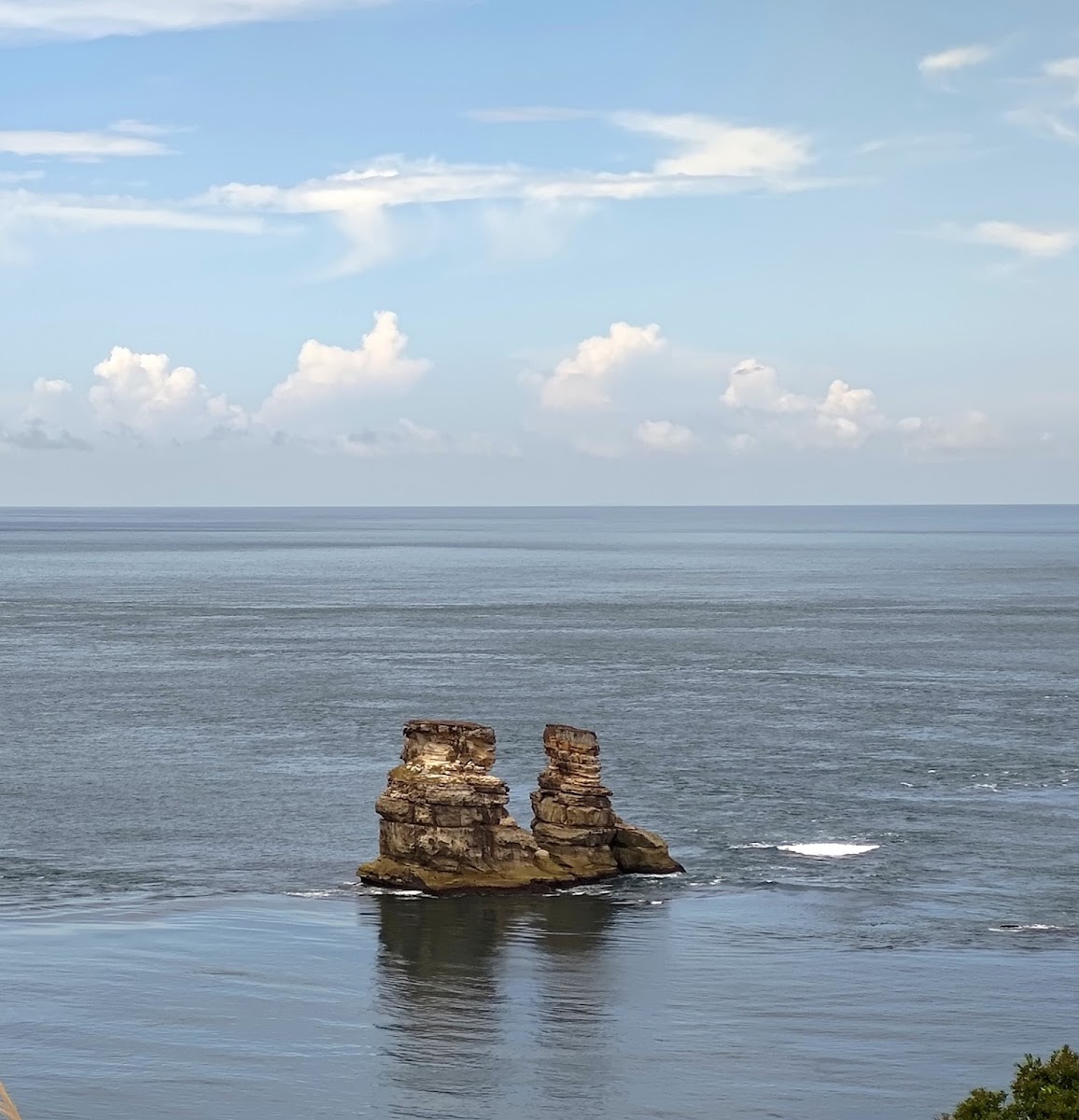 燭台雙嶼兩座砂岩礁岩並立遼闊海面，藍天白雲，夏日晴朗
