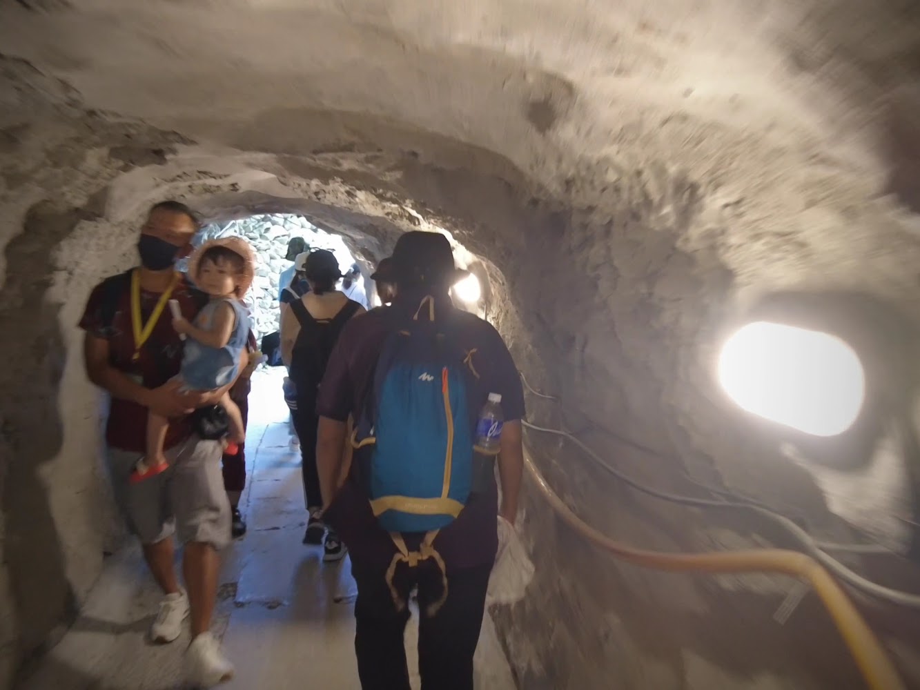 一群人在岩石隧道內行走,隧道內有照明