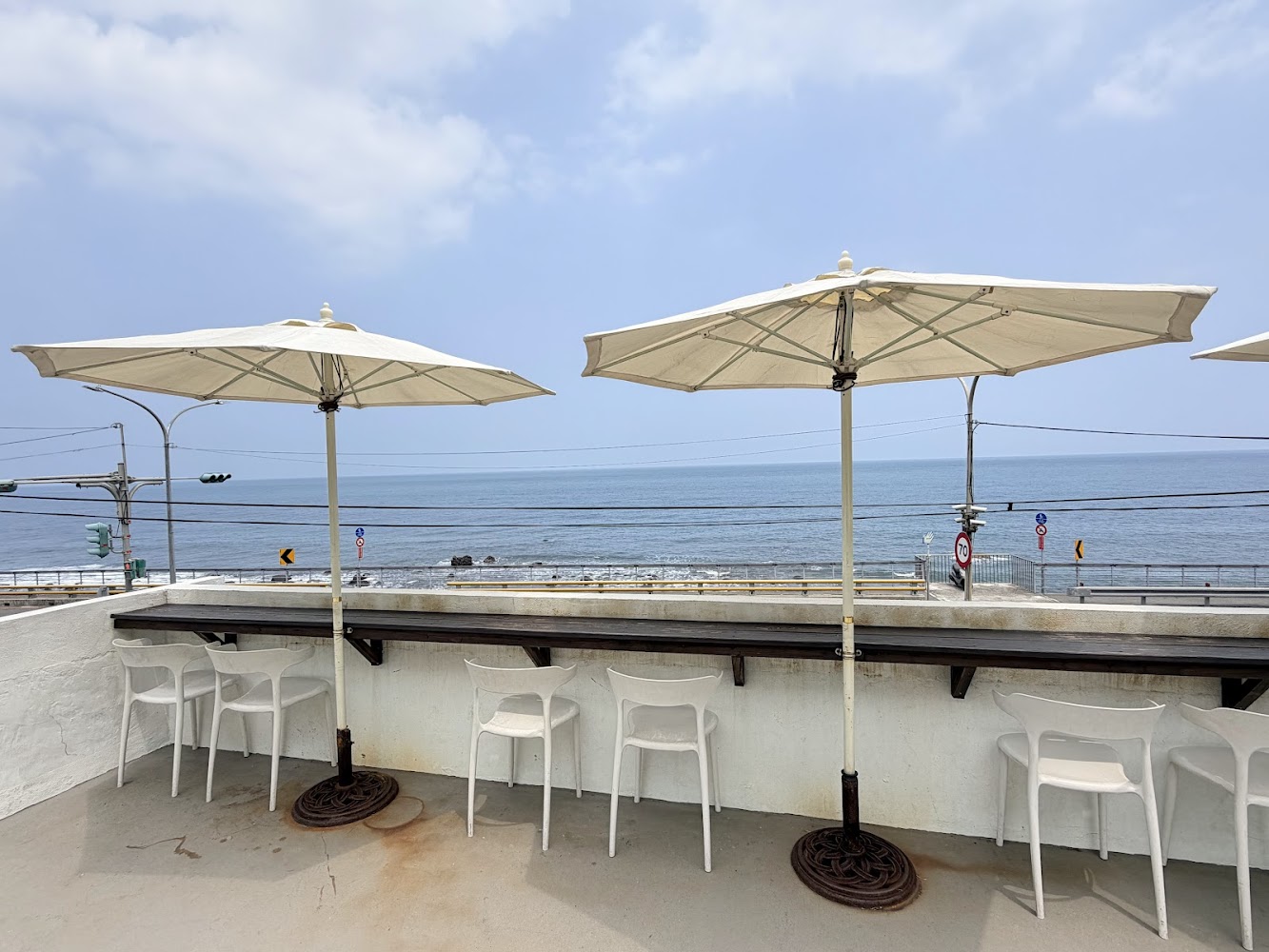 海邊露天座位區有白色遮陽傘與椅子面向大海