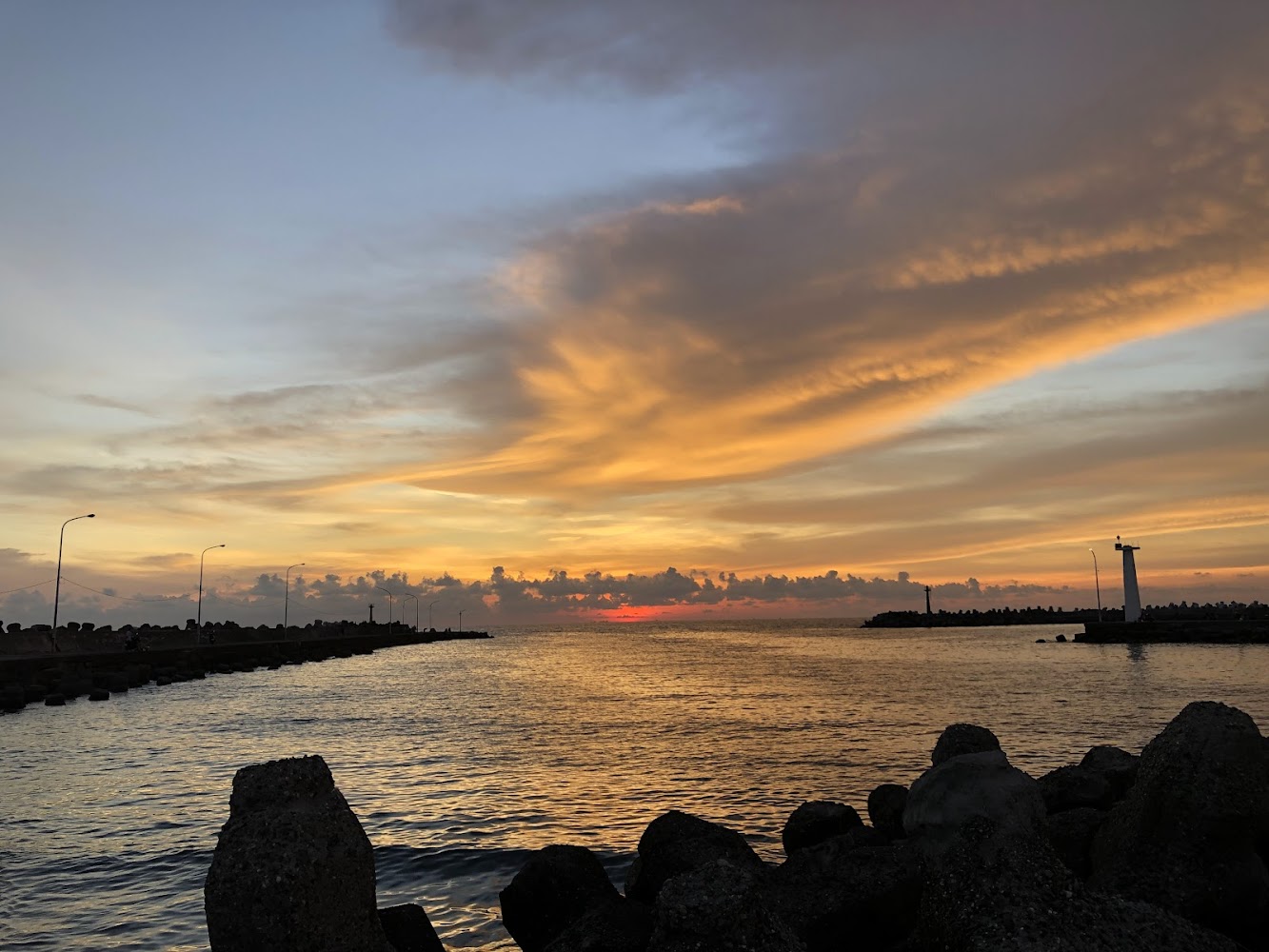 橘黃色夕陽與防波堤燈塔景色