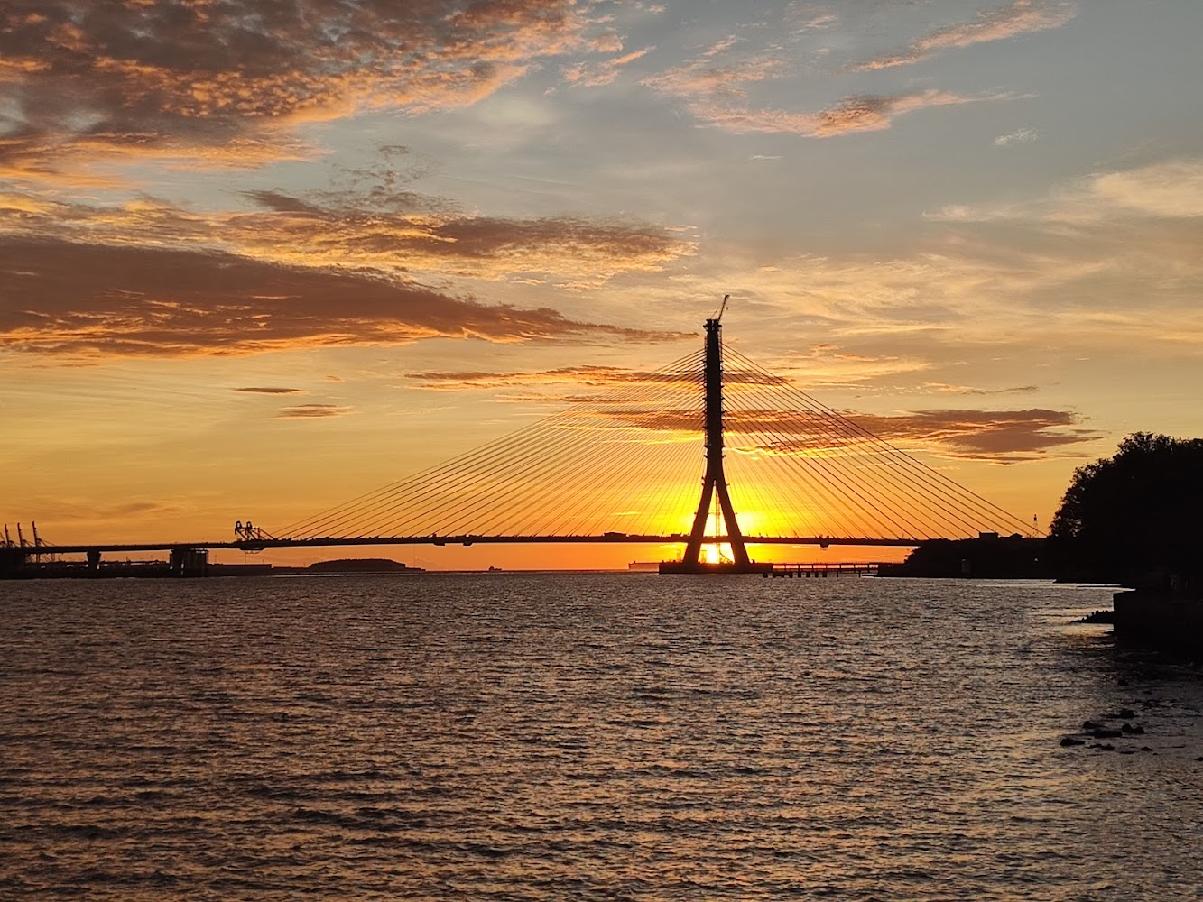 跨海大橋背景為夕陽與金色雲彩,前景是平靜海面