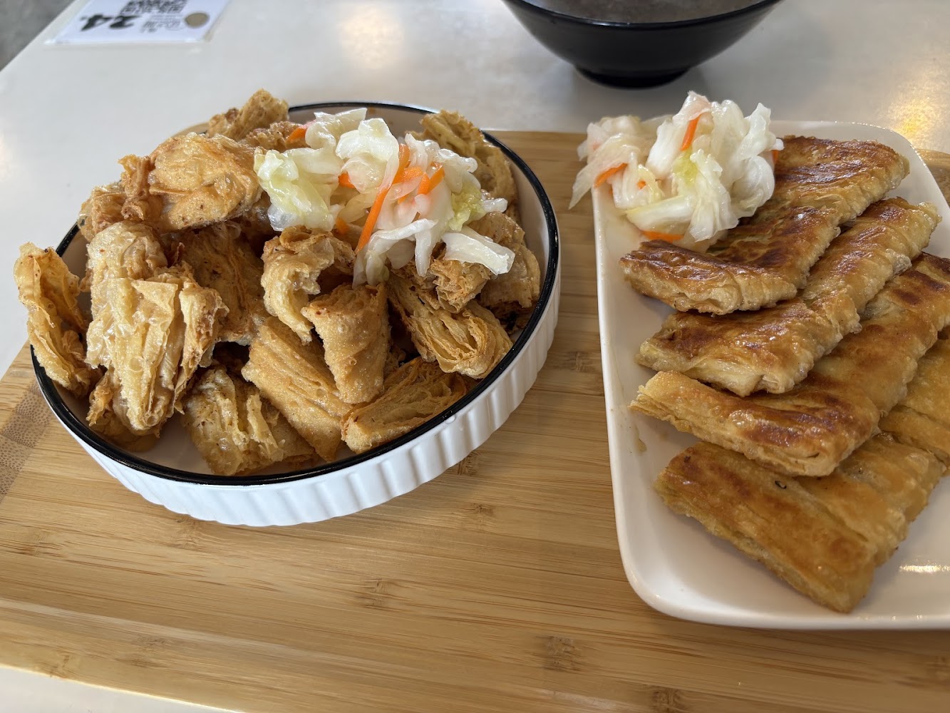 兩盤美食，左邊炸豆皮配泡菜，右邊金黃蔥油餅也附泡菜