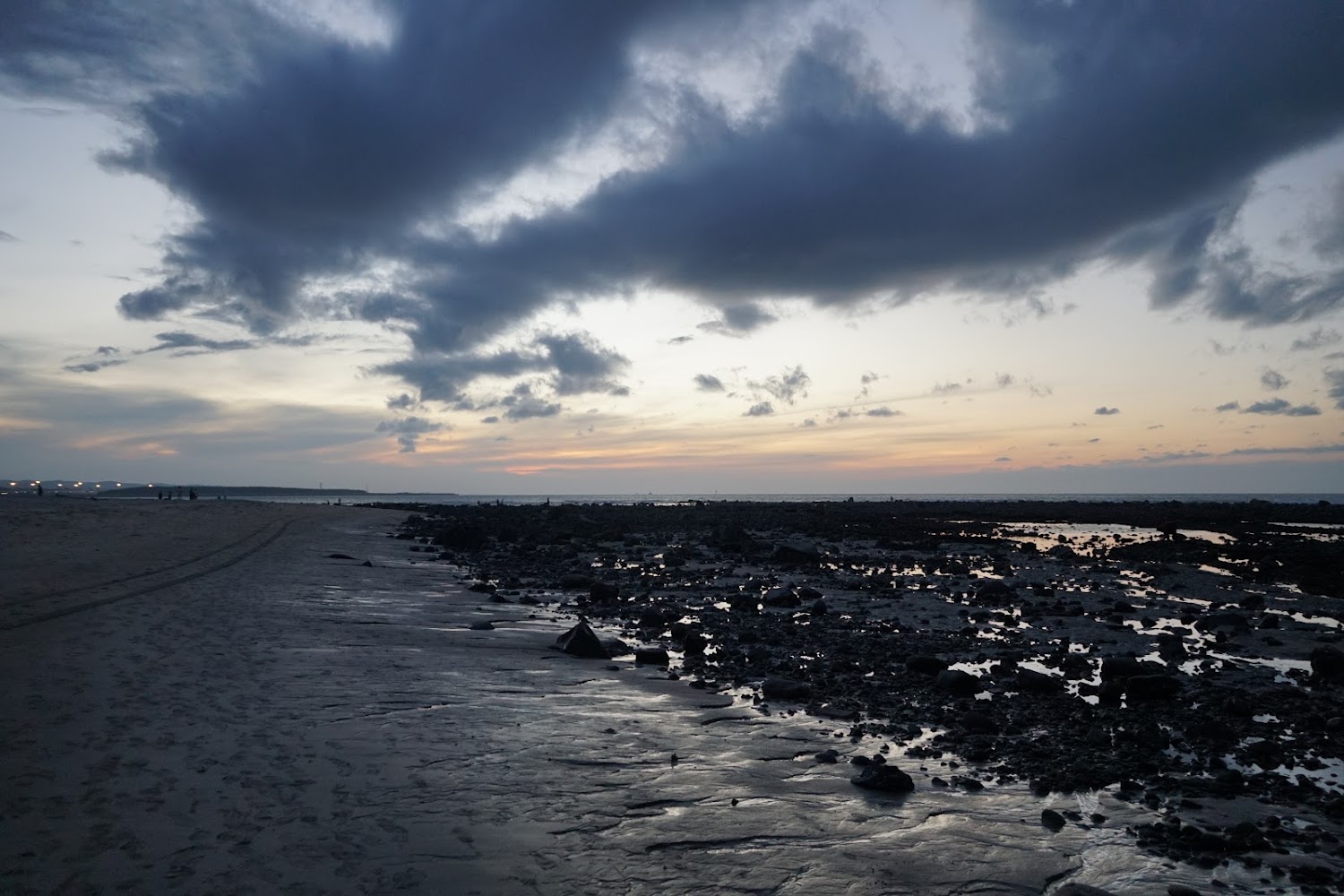 傍晚海邊潮間帶沙灘與礫石在夕陽餘暉下的景色