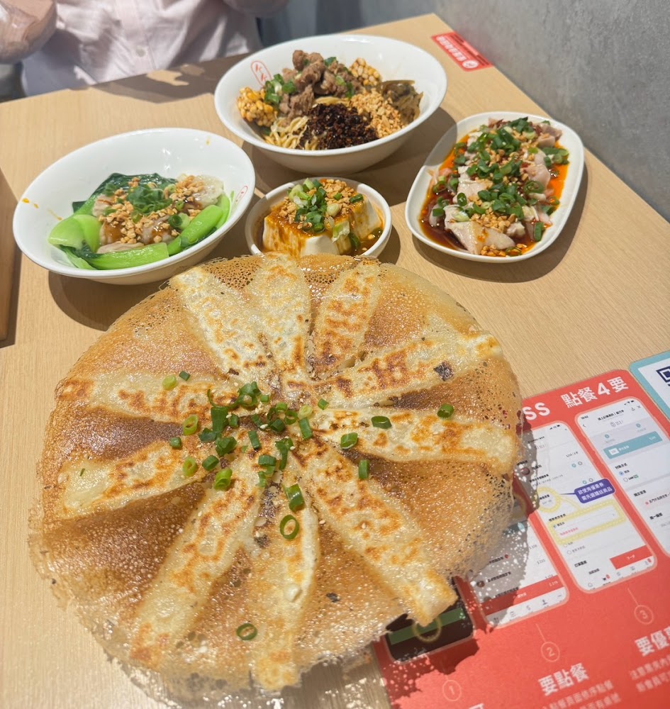 炙燒煎餃與多道小菜，包含麻醬麵、雞肉與豆腐。