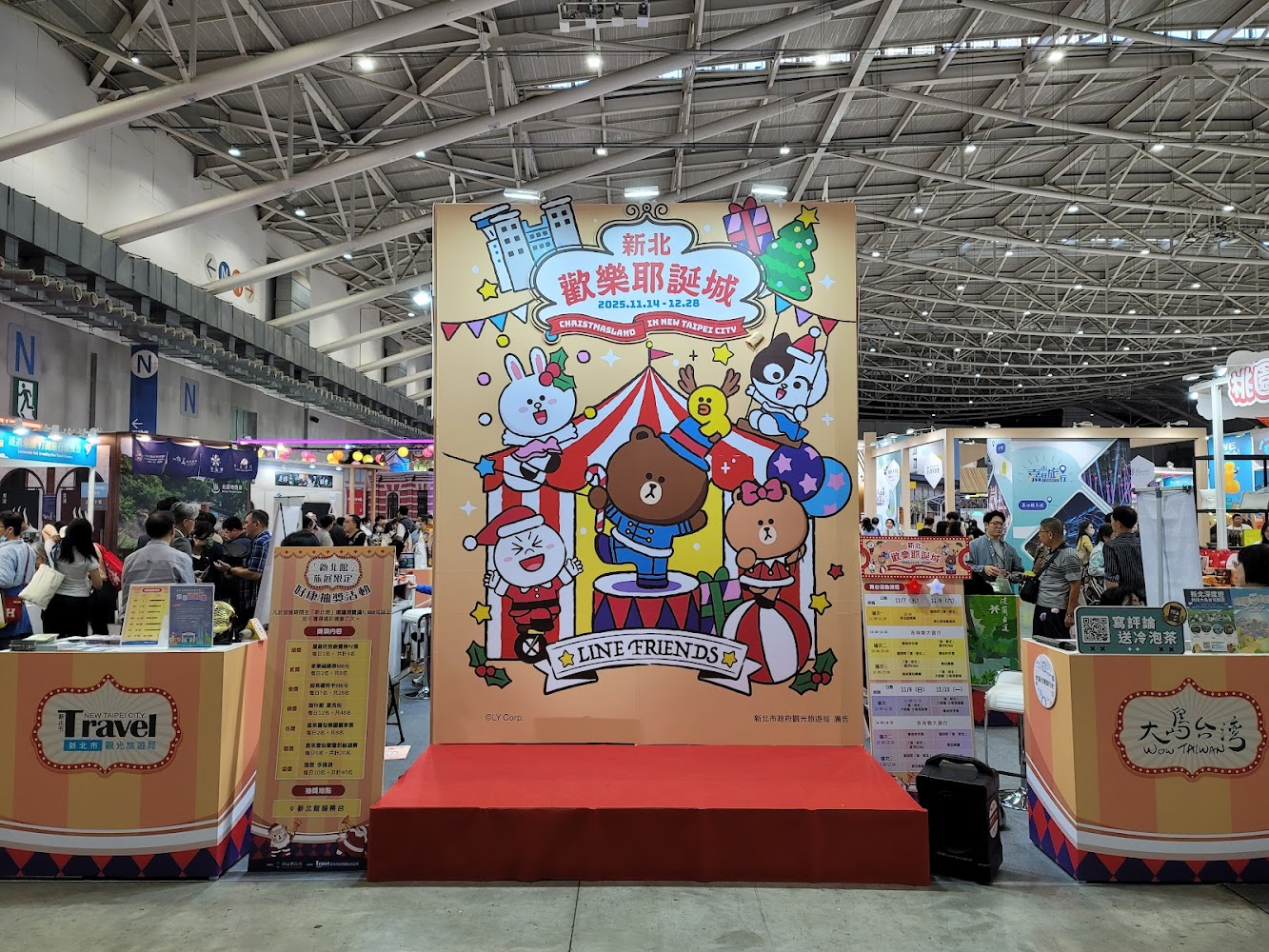 展場中央有LINE FRIENDS聖誕主題立牌,周圍是新北歡樂耶誕城資訊攤位與參觀民眾