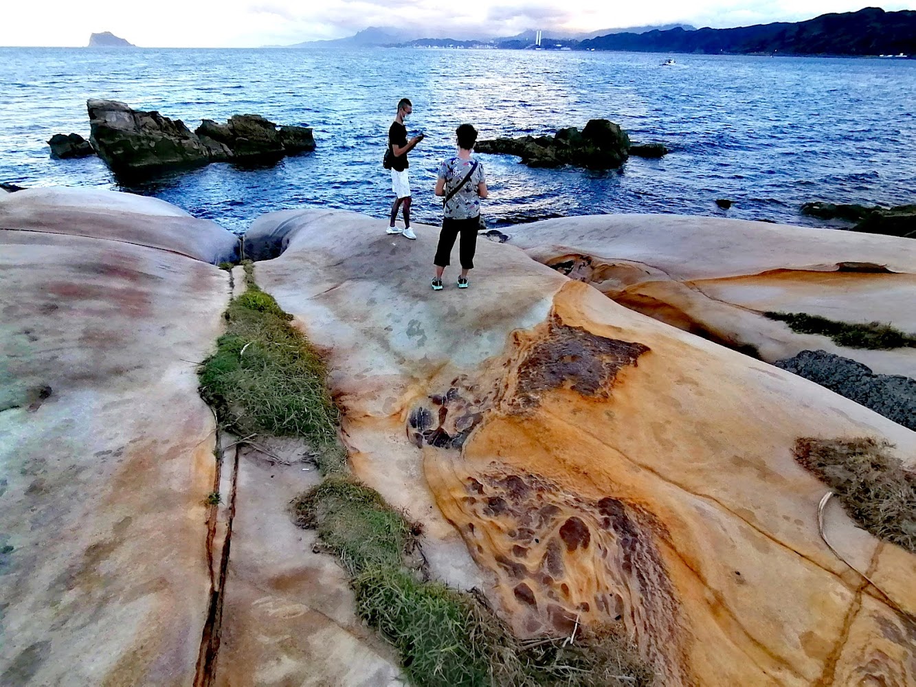 兩人在奇特岩石地形上與海景山景合影