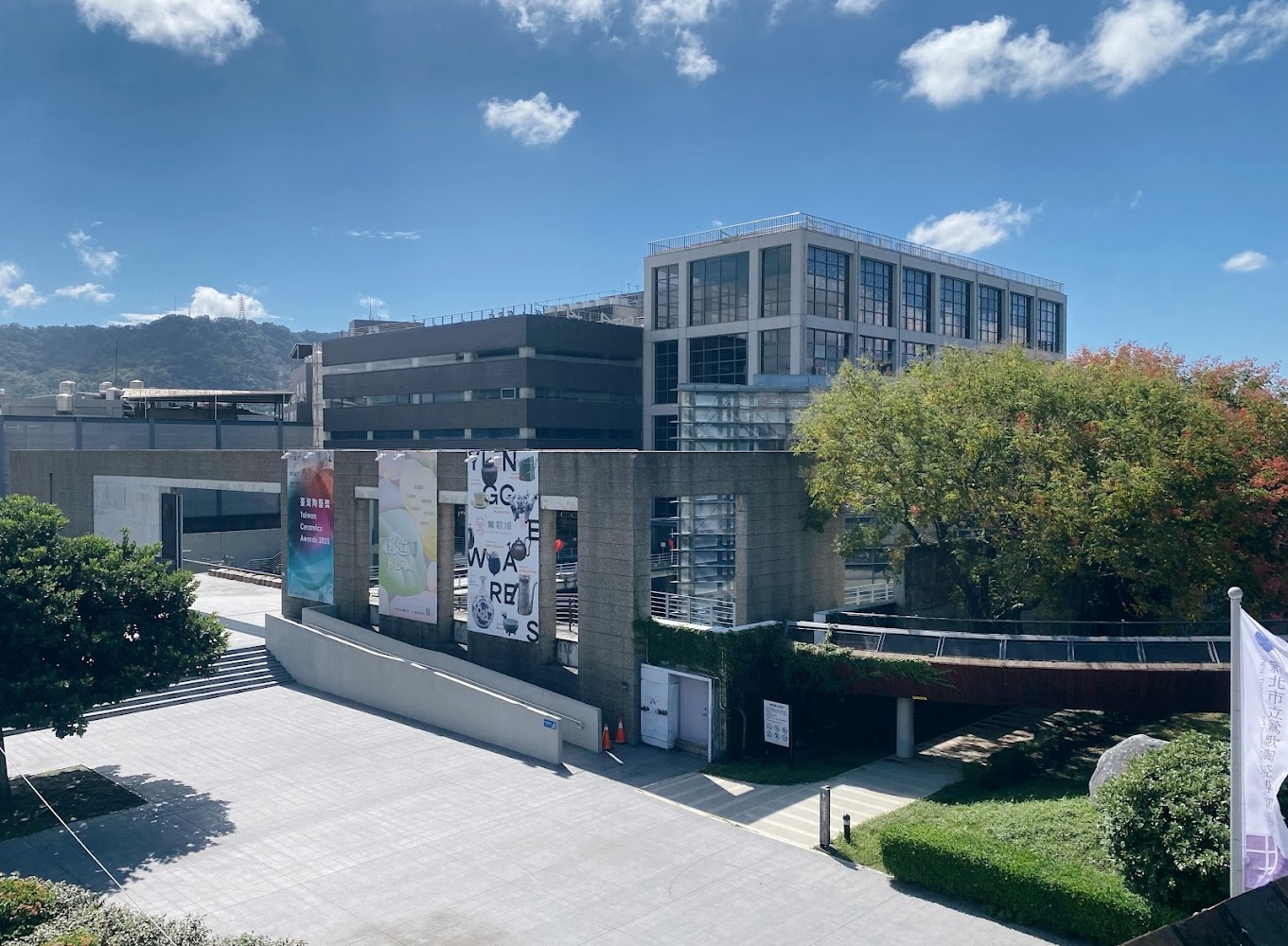 廣場前方有大型樹木與展覽布條的館舍景觀