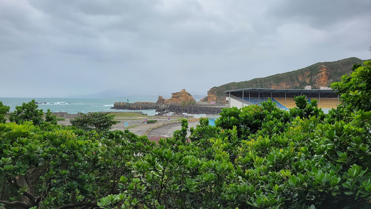 綠色植物防波堤與遠方奇岩海岸線
