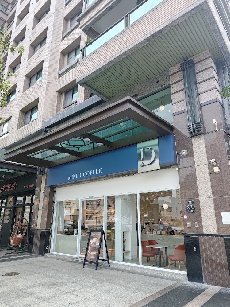 街邊一家名為MINLD COFFEE的咖啡廳店面,外觀簡約現代,設有大片落地窗,可以看到室內座位區,店門前有廣告看板,整體氣氛舒適文青。