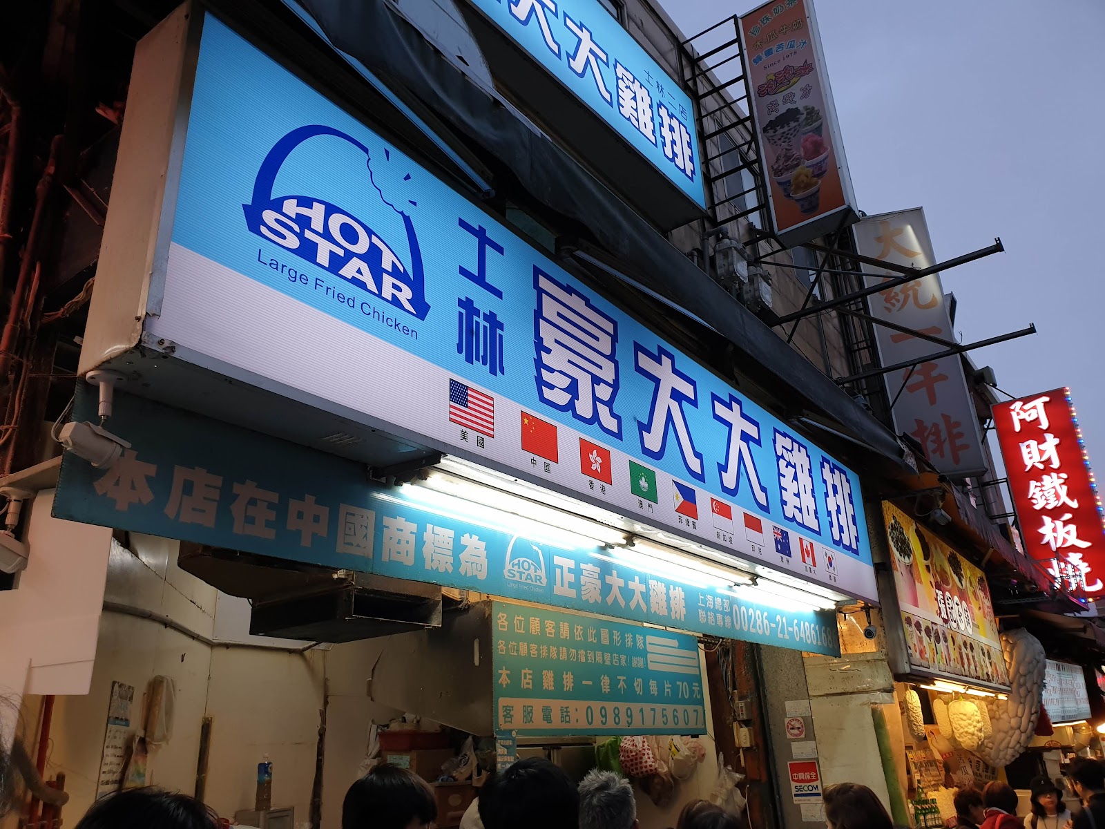 士林豪大大雞排夜晚店面，招牌下方有多國旗幟，顯示其國際知名度