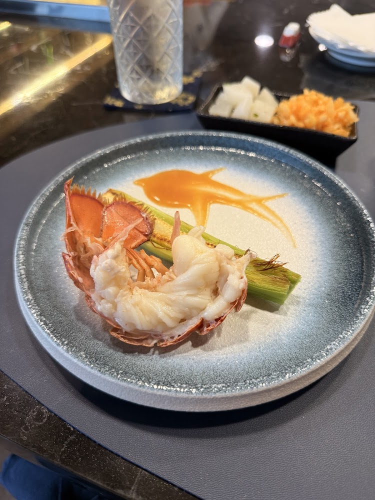 半隻龍蝦肉搭配蘆筍與創意醬汁裝飾的精緻海鮮料理