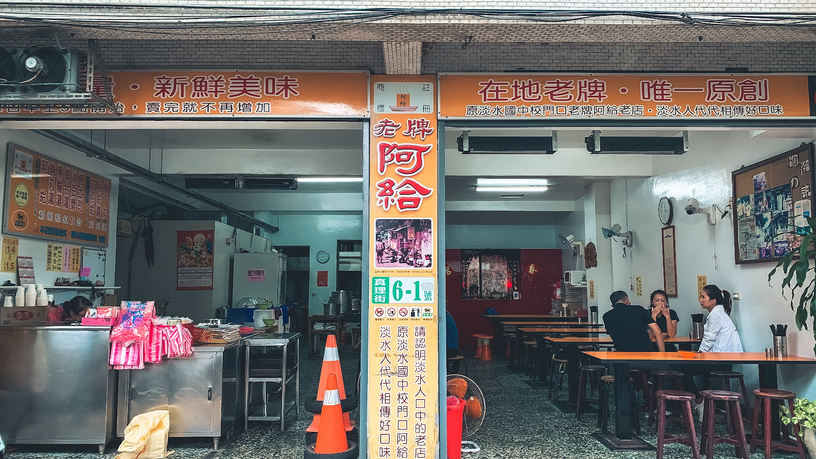 淡水老牌阿給創始店外觀，橙黃色招牌，店內座位一覽