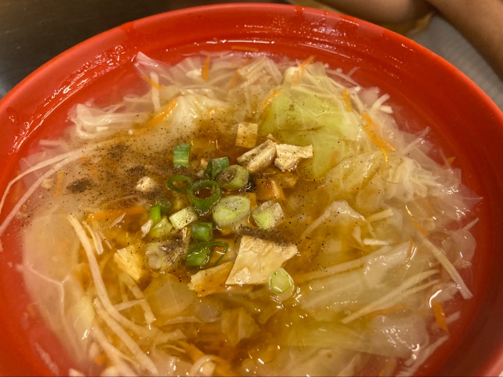 清湯中有高麗菜紅蘿蔔絲蔥花豆皮和黑胡椒