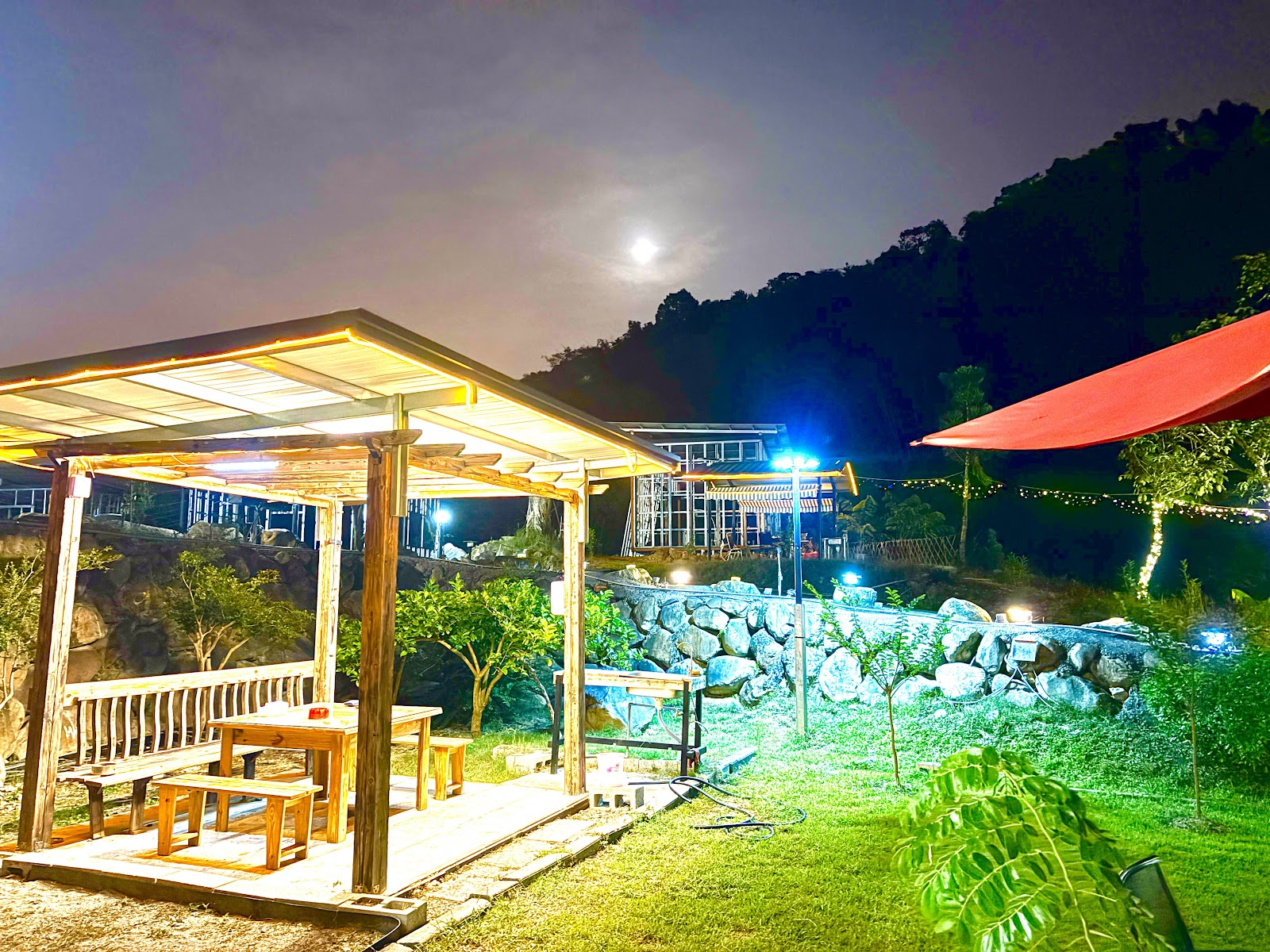 黑爵士民宿夜晚戶外木製涼亭，彩色氛圍燈與岩石庭院