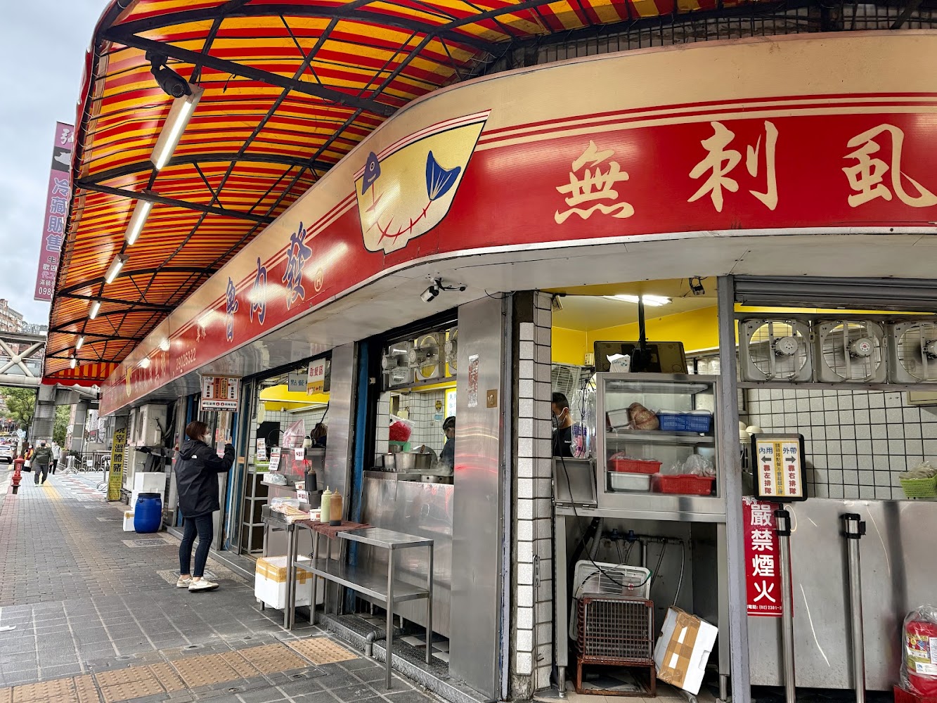 台灣小吃店外觀，紅色遮雨棚與排隊點餐人潮