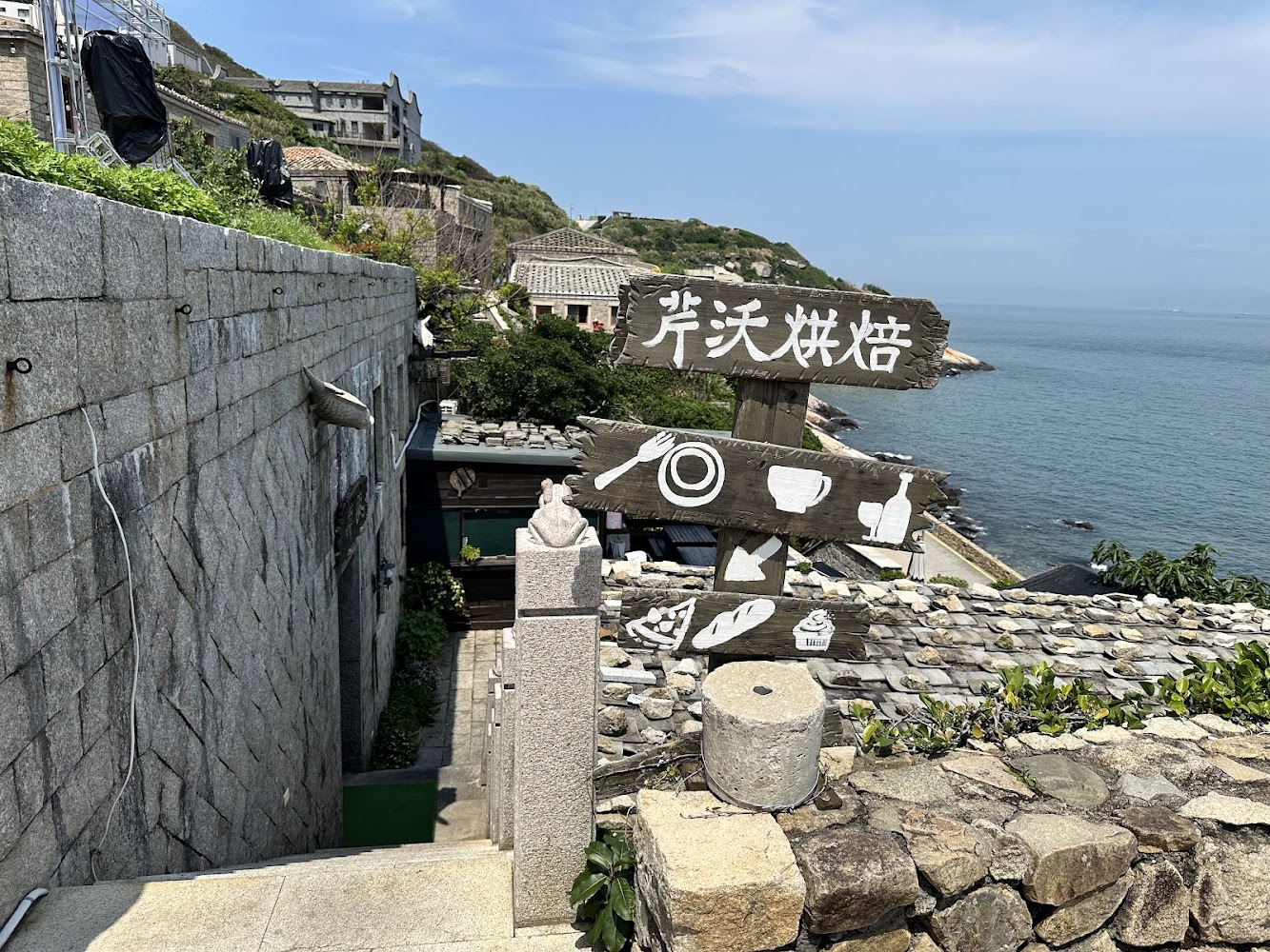 石頭階梯旁可見芹沃烘焙木製招牌與海景