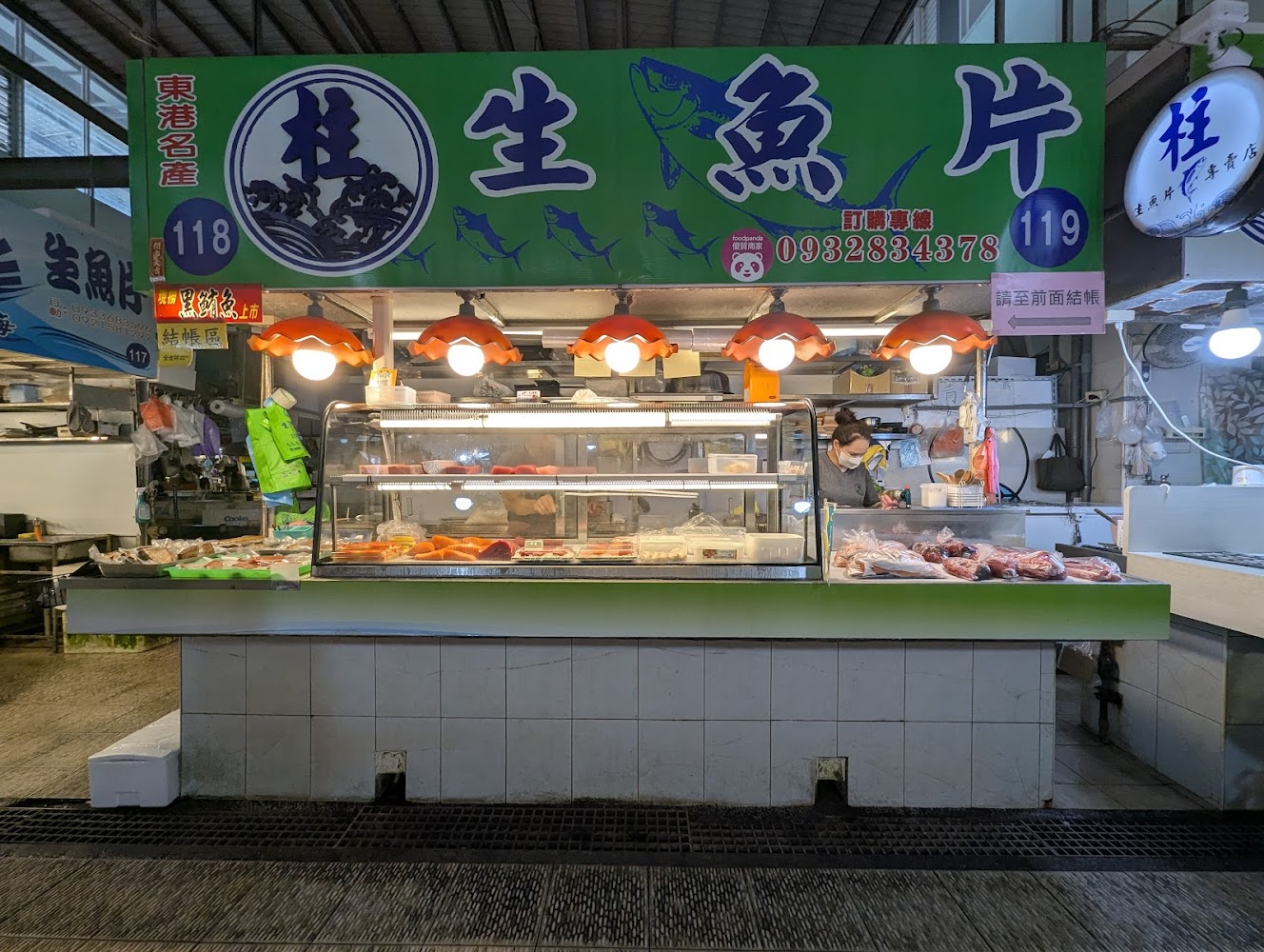 華僑市場內部生魚片攤位燈光明亮，各式海鮮整齊陳列。