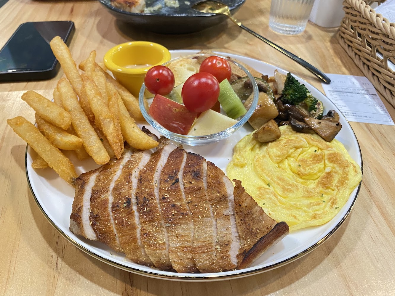 早午餐餐盤包含厚切豬排、薯條、水果沙拉、炒蛋、炒菇與蔬菜