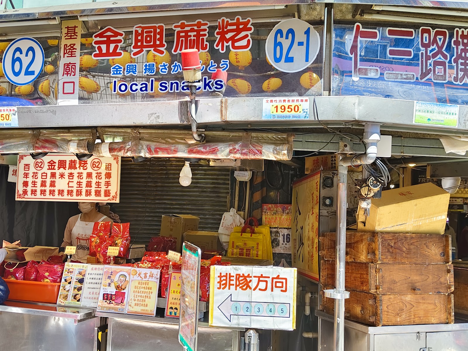 基隆廟口62號金興蔗粿攤位，排隊方向指示牌，攤前擺滿傳統糕點