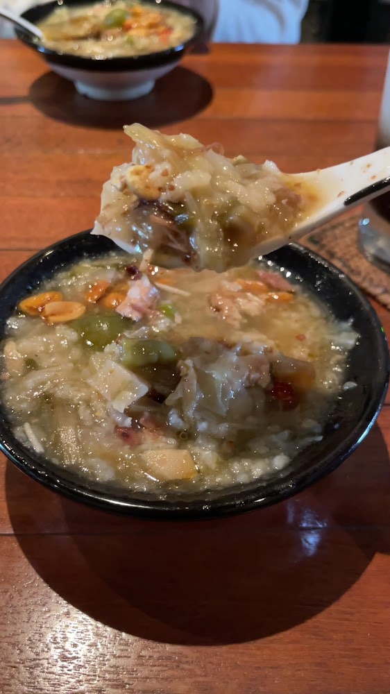 這張圖片主要是一碗豐富的熱粥，裡面有花生、豆腐、蔬菜及肉類，湯汁濃稠，色彩豐富，呈現溫暖可口的感覺，適合當早餐或簡餐食用。