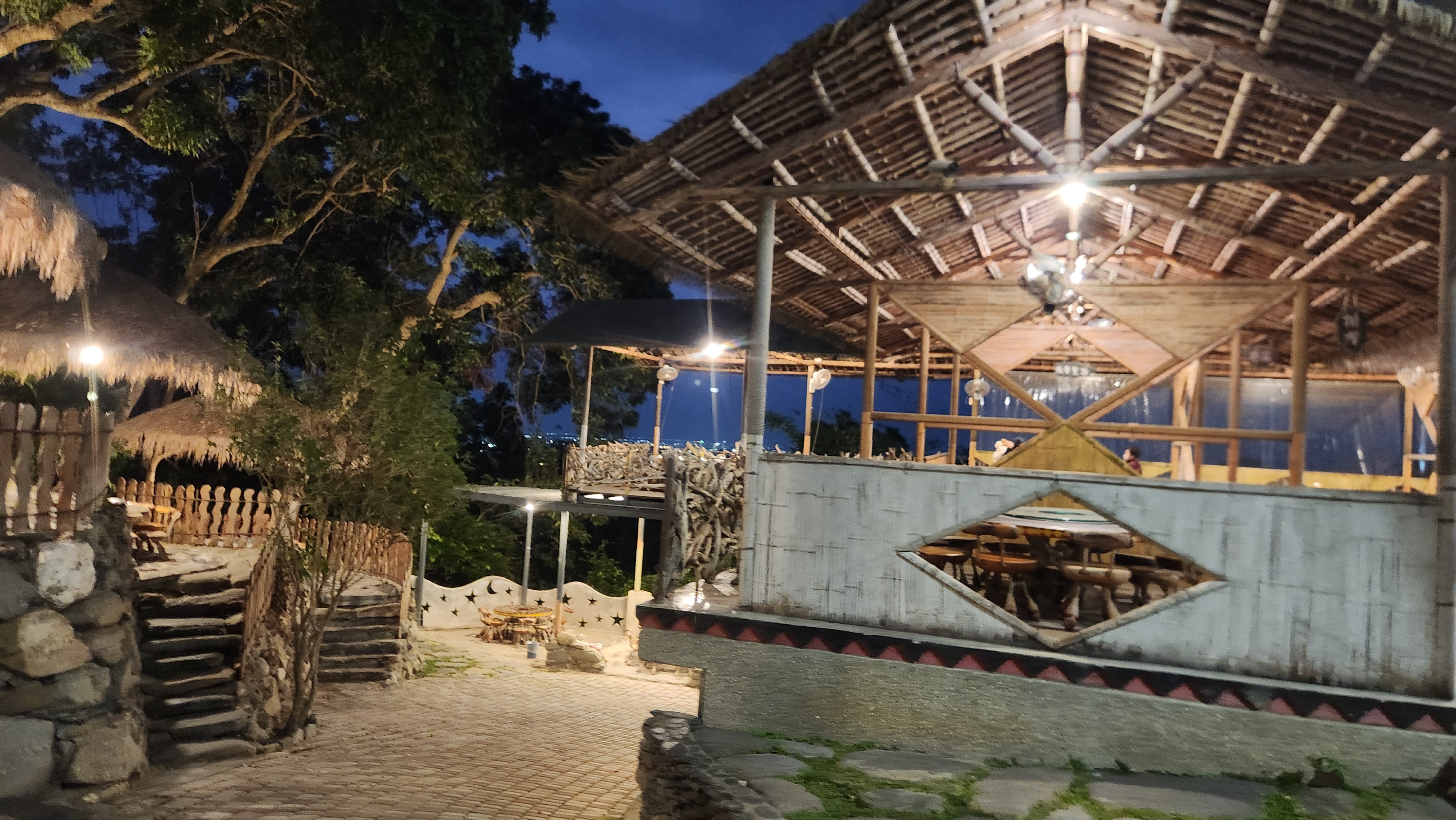 以竹子和木材建造的露天餐廳，周圍樹木環繞，充滿自然與原始風格