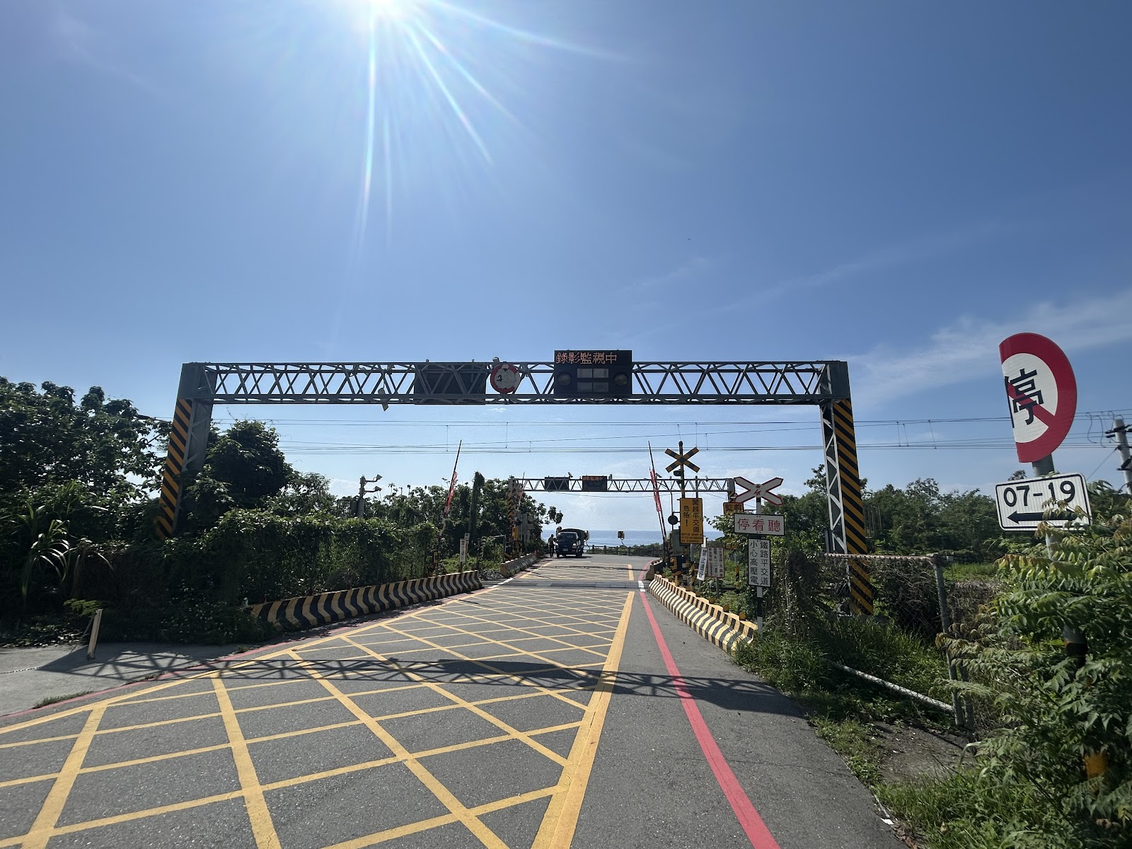 太麻里平交道鐵製橫桿近拍，黃色路面標線，拍影拍照中電子看板，台東景點
