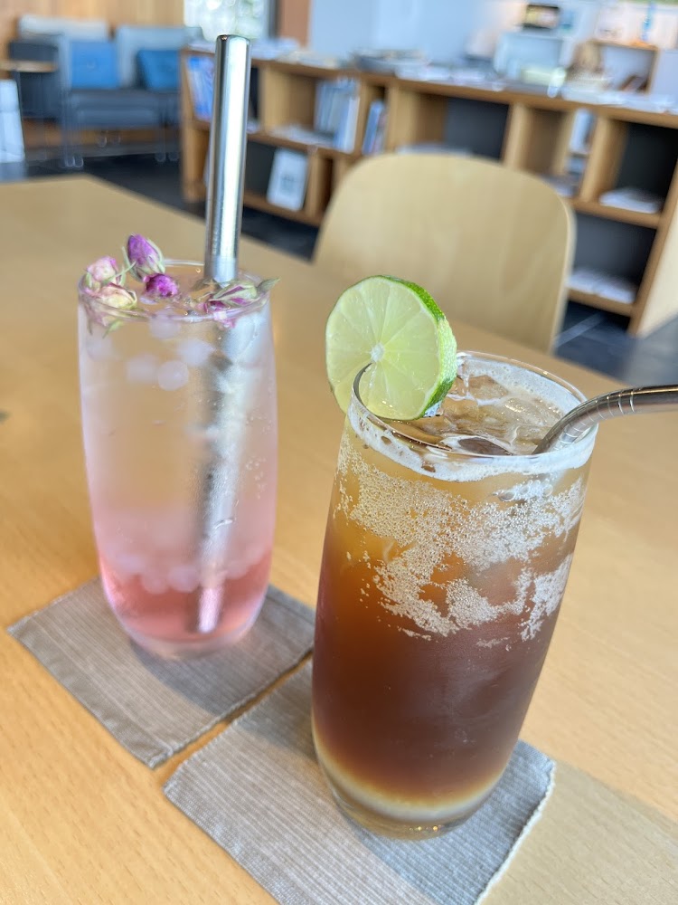 桌上擺放兩杯精緻飲品，一杯是粉色氣泡飲，另一杯是咖啡氣泡飲
