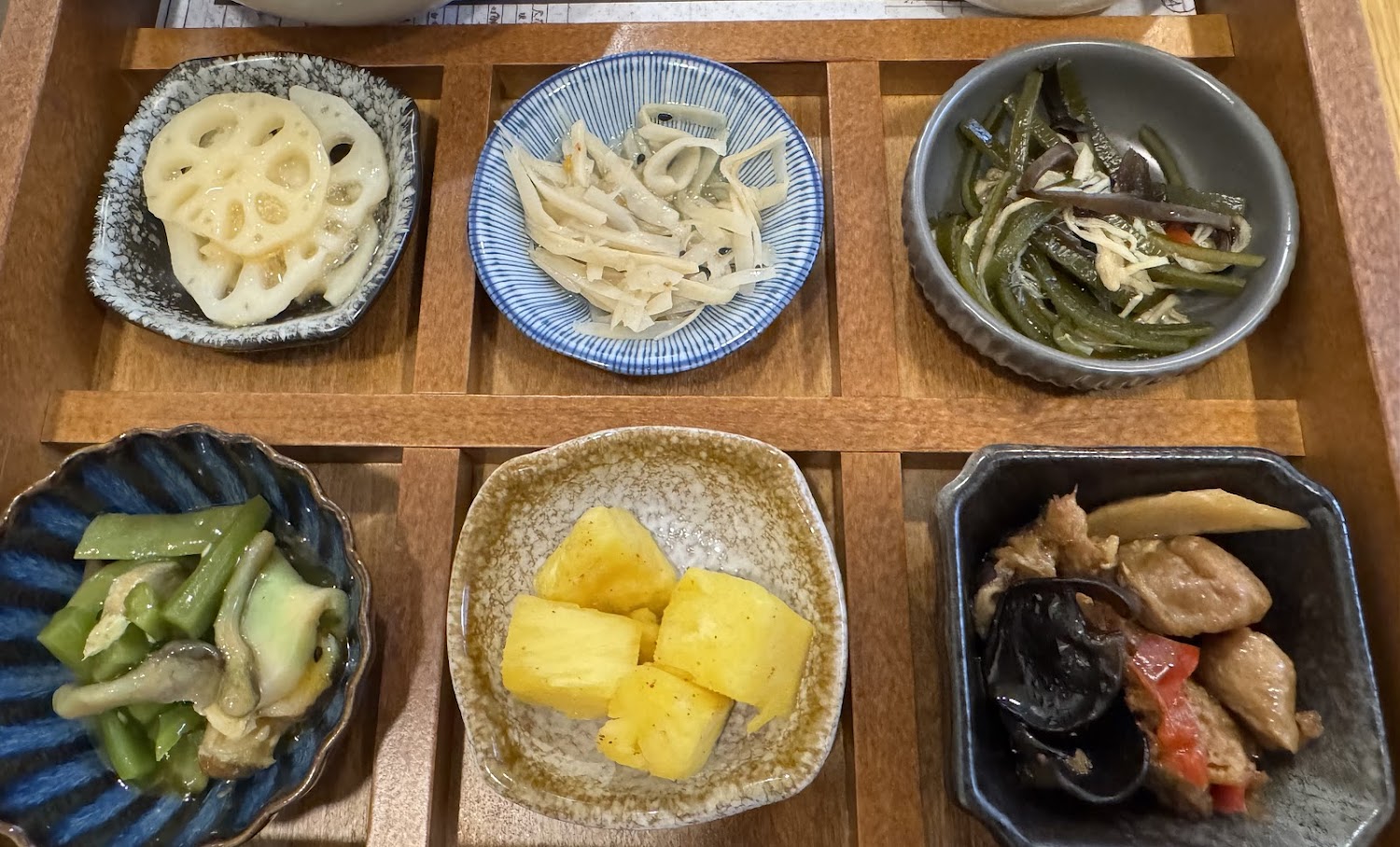六道日式小菜,包括蓮藕片海帶絲四季豆鳳梨與滷雞肉木耳