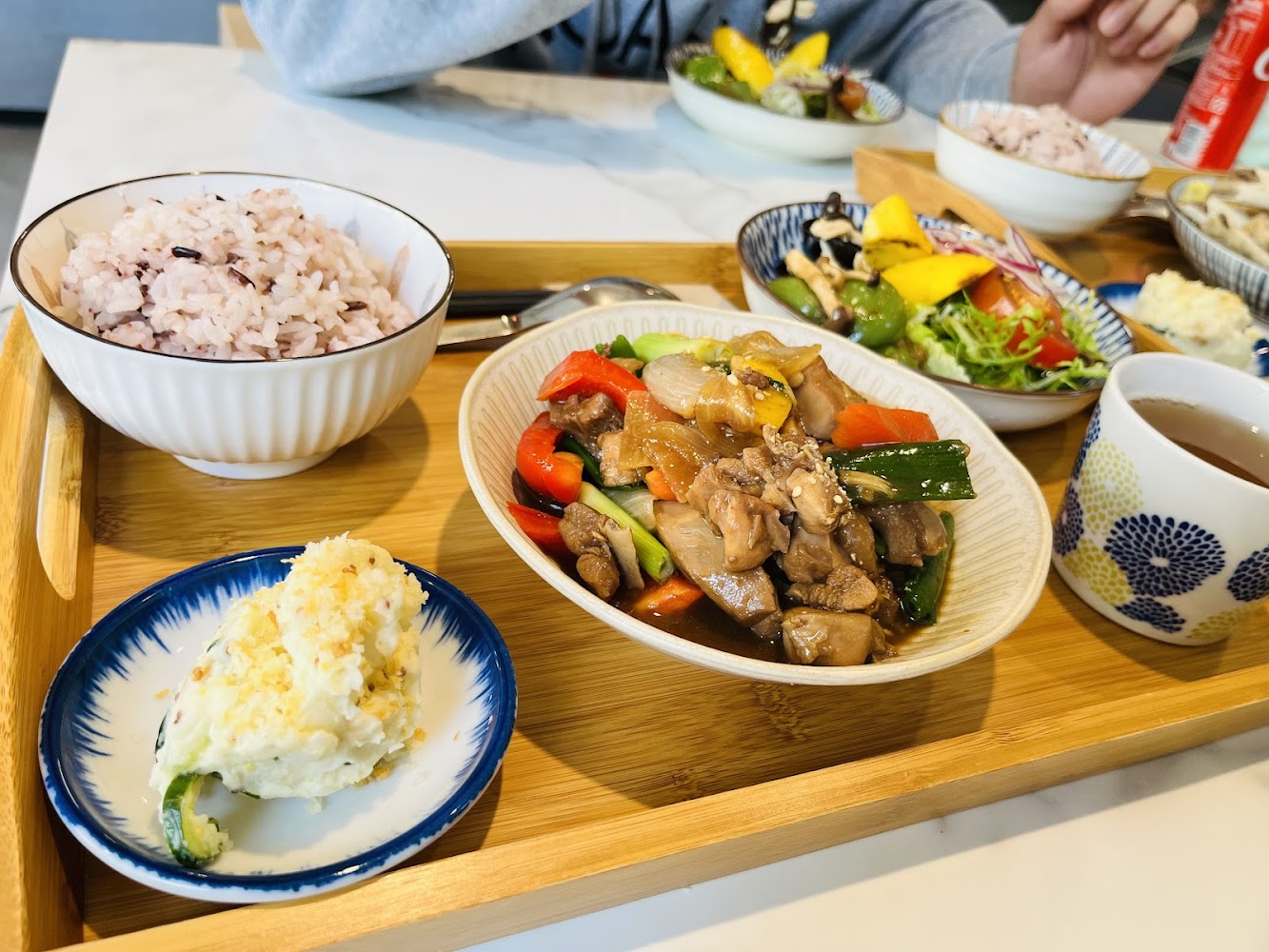 五穀飯搭配炒雞肉蔬菜、馬鈴薯沙拉與茶的豐富套餐