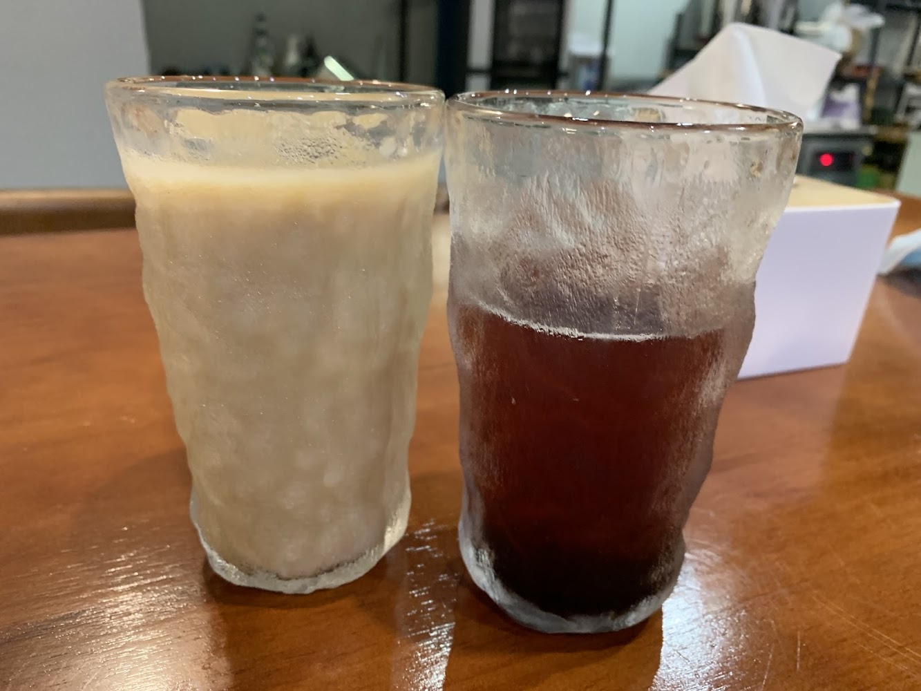 兩杯飲料放在木桌上，一杯淺色一杯深色