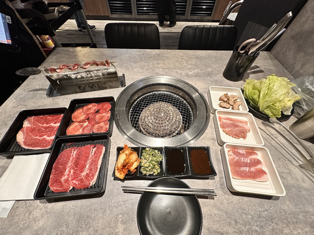 一桌日式燒肉，有各種切片牛肉、豬肉、蔬菜、生菜葉、泡菜和調味醬料