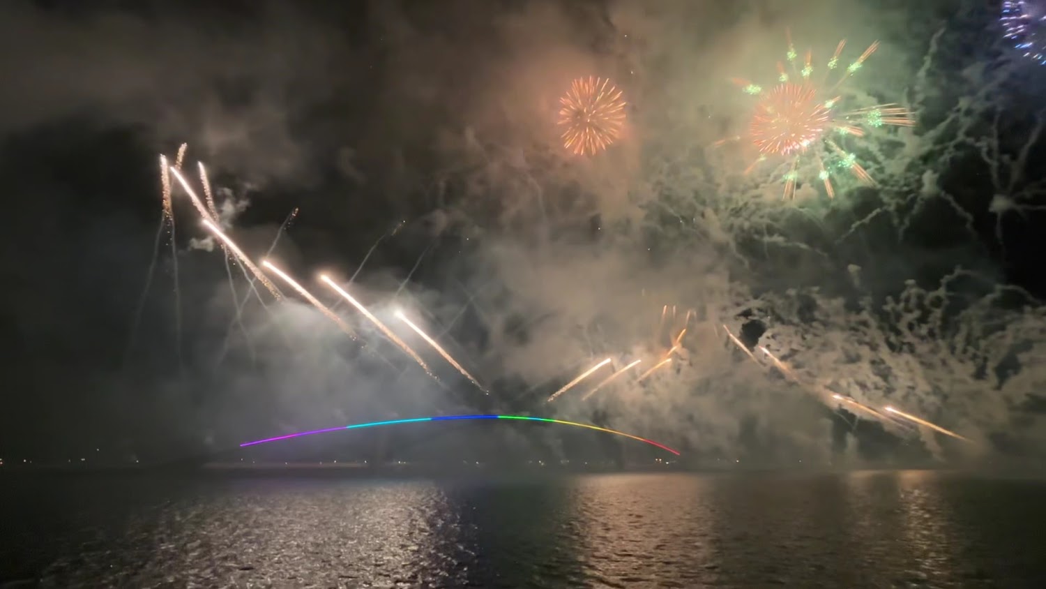 煙火照亮夜空下的彩虹燈光拱橋