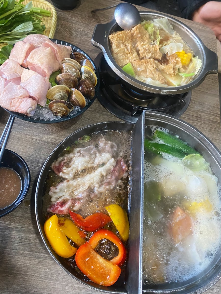 誠石火鍋雙拼鍋底俯視圖，左側麻辣右側清湯，旁邊擺有海鮮肉片