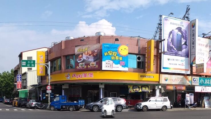 丹丹漢堡梓官店外觀，黃色招牌，街角位置